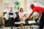 a man and woman sitting on a couch watching a Glass Doctor service professional install a glass tabletop
